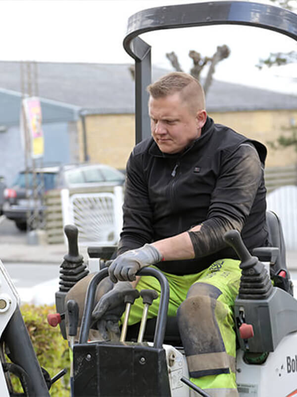 Asmuo, dėvintis NordicHeat šiluminius drabužius, dirba su Bobcat statybvietėje. Drabužiai užtikrina komfortą ir judėjimo laisvę aktyviose lauko aplinkose. Nėra matomo teksto.